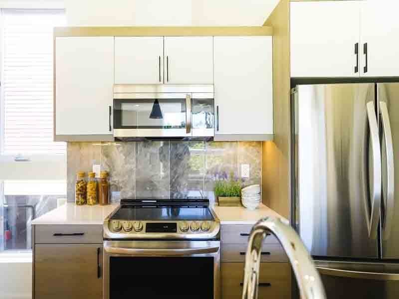 A kitchen with a stove , refrigerator , microwave and sink.