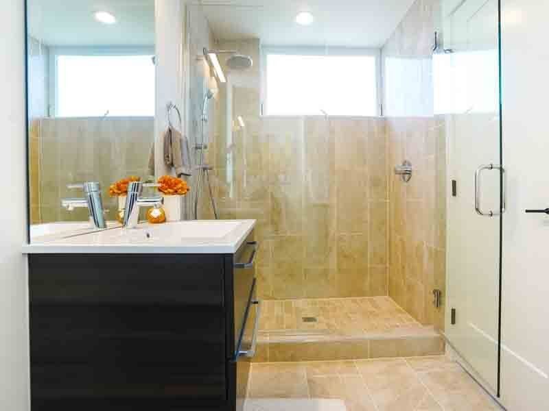 A bathroom with a sink , mirror and walk in shower.