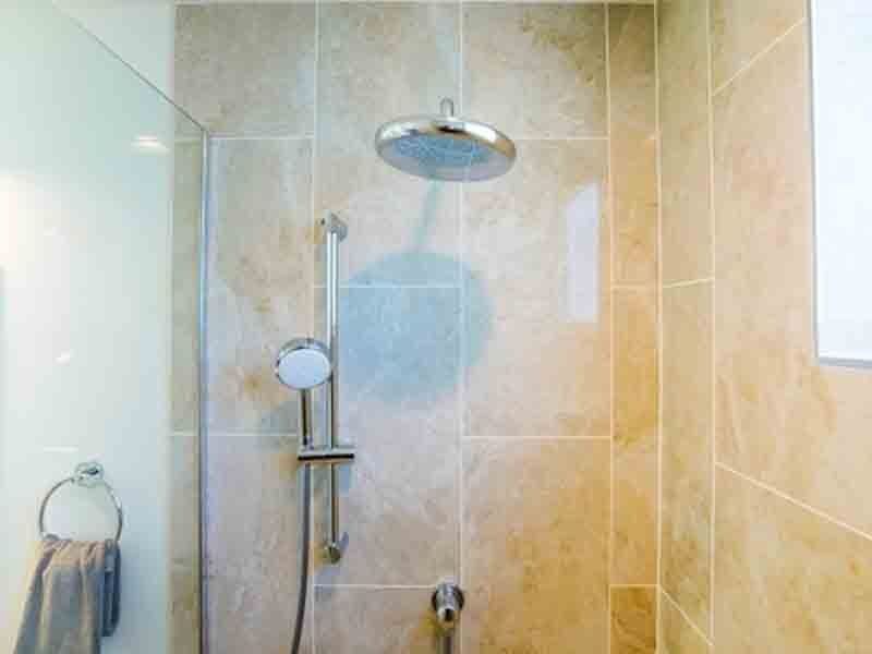 A bathroom with a shower head and a towel hanging on the wall.