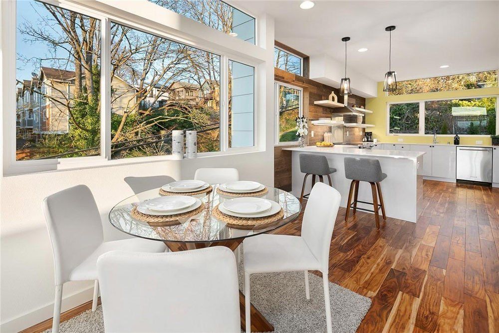 A dining room with a glass table and white chairs.