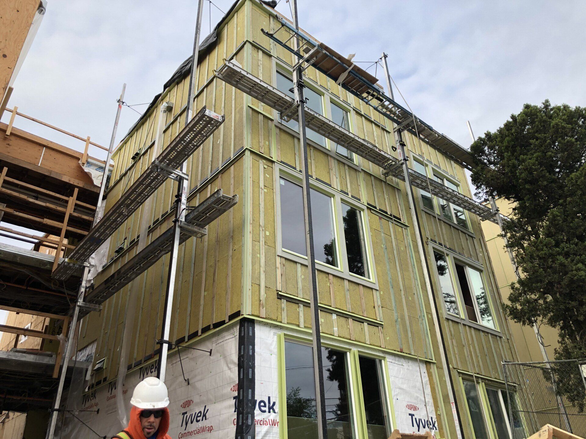 A man in a hard hat is standing in front of a building under construction.