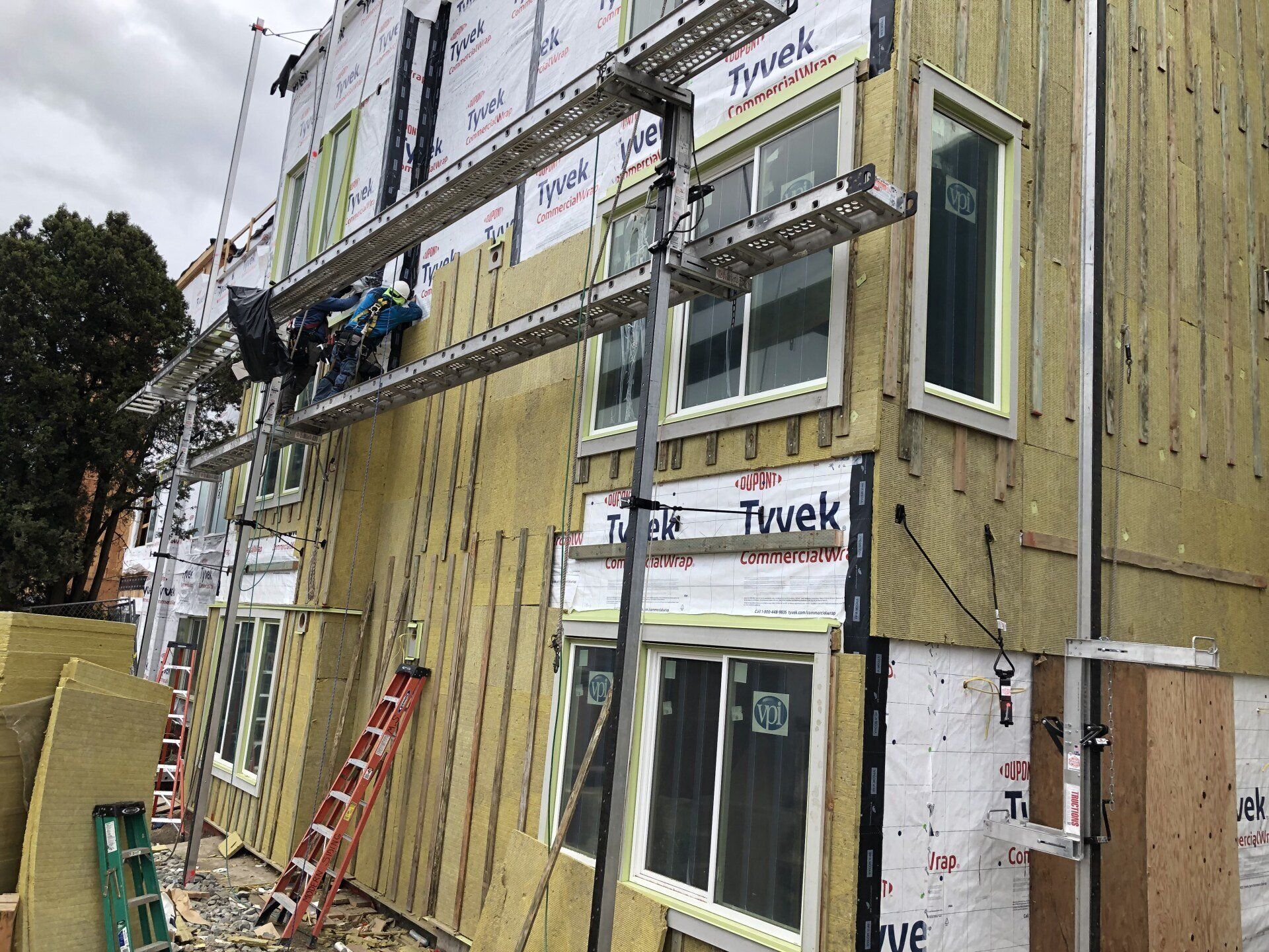 A building is being built with scaffolding and a ladder.