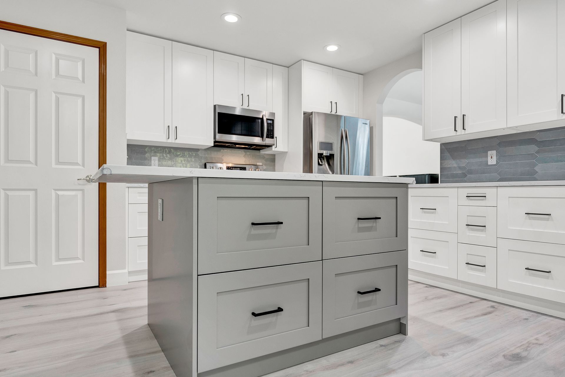A kitchen with white cabinets and a large island in the middle.