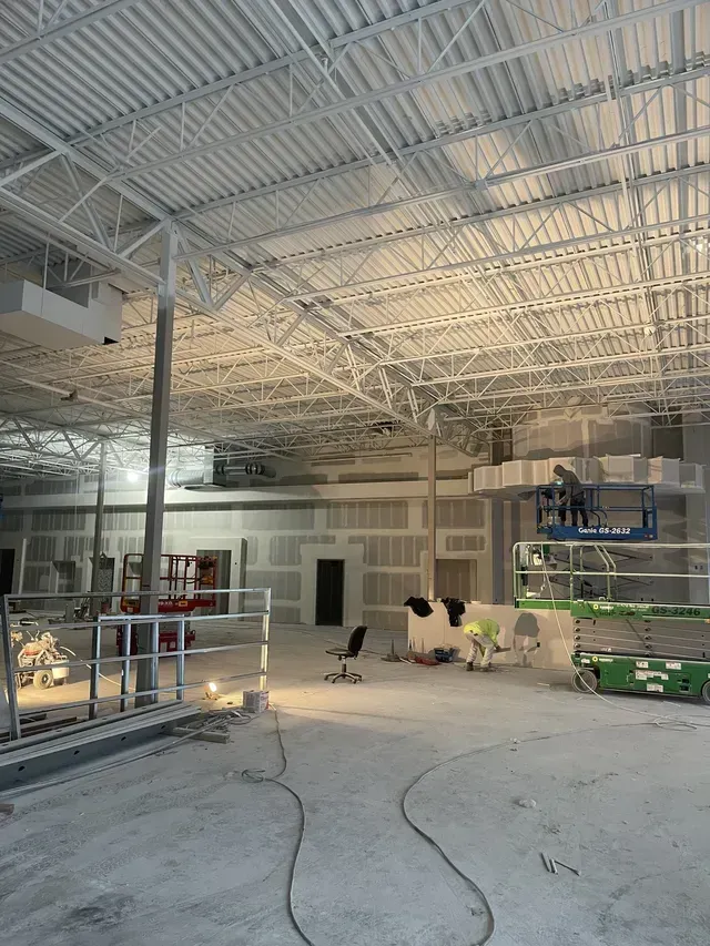 A cow is sitting in the middle of a large building under construction.