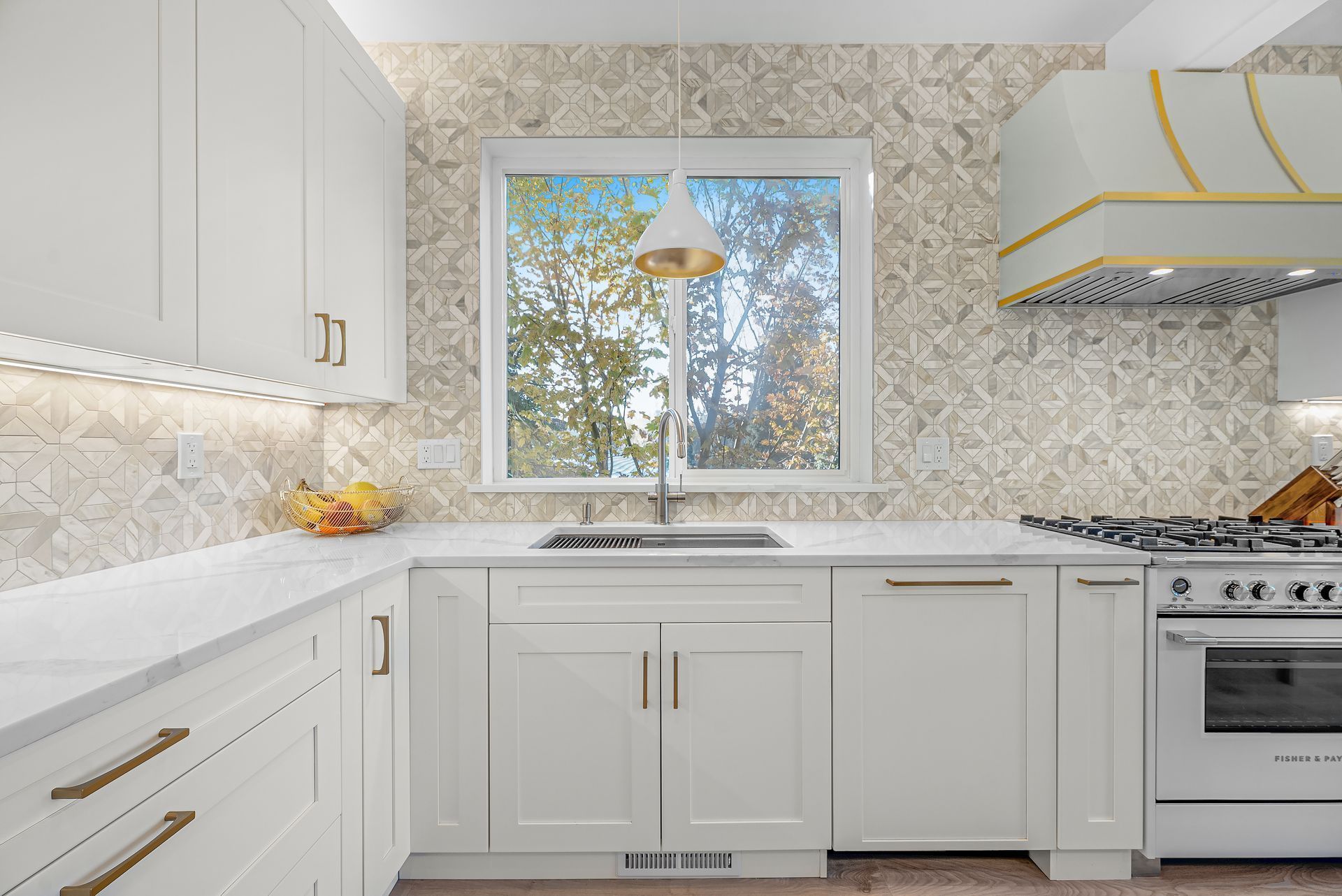 A kitchen with white cabinets , a stove , a sink , and a window.