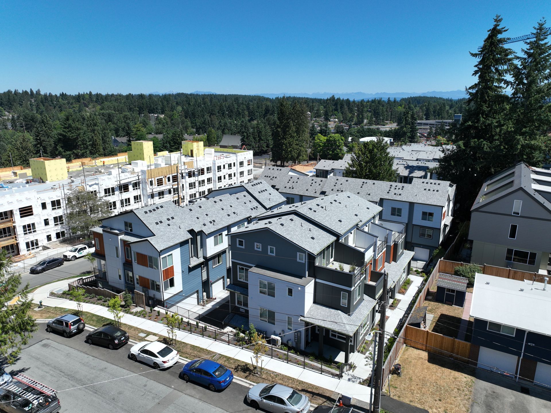 An aerial view of a residential area with a lot of buildings and cars parked on the side of the road.