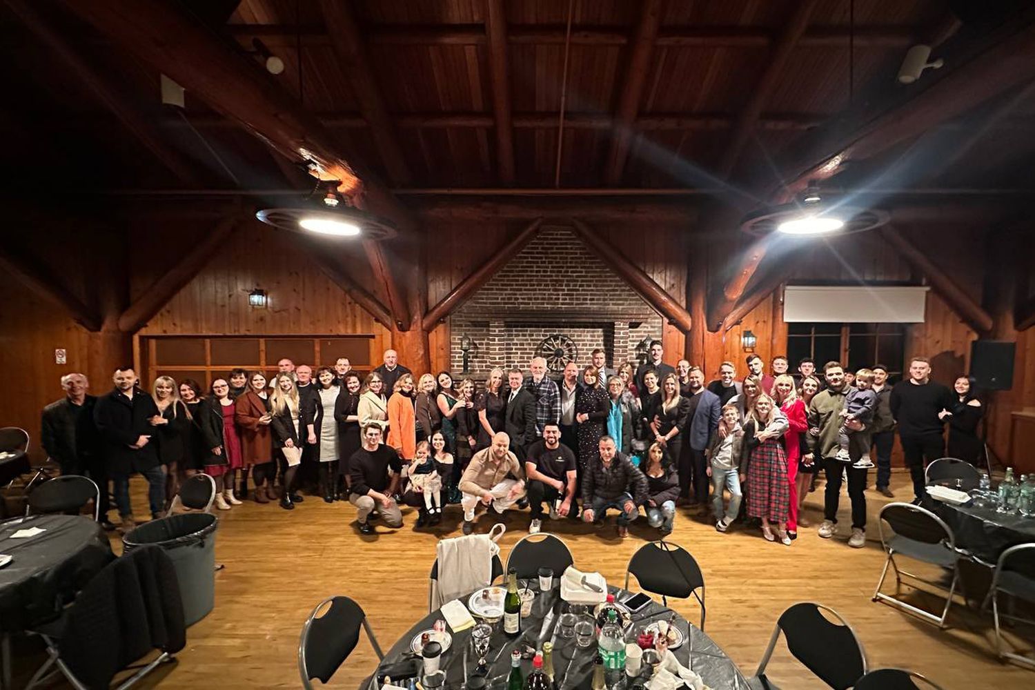 A large group of people are posing for a picture in a wooden room.