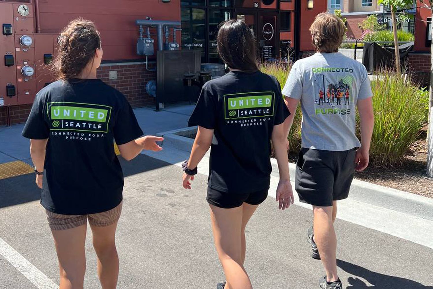 Three people wearing united shirts are walking down the street.