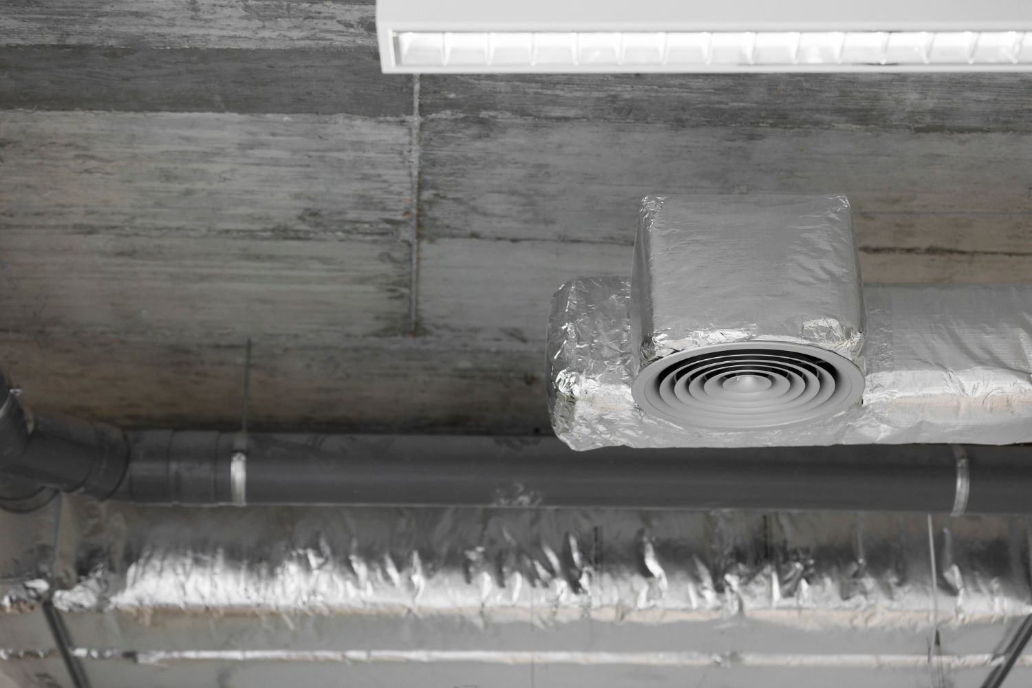 A close up of a ventilation system on the ceiling of a building.