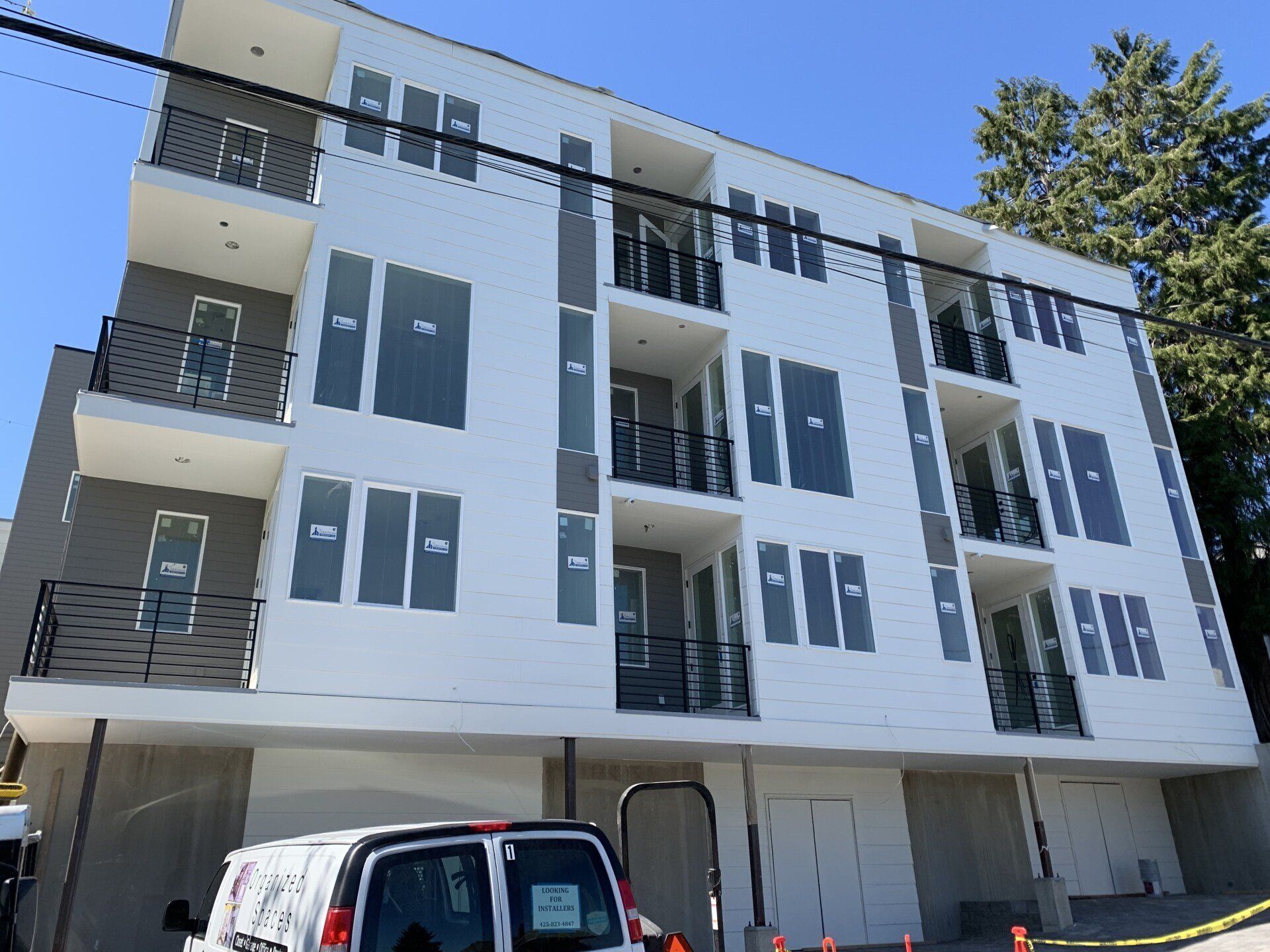 A white van is parked in front of a large apartment building