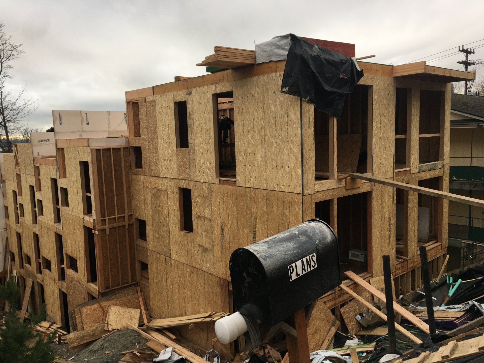 A mailbox is sitting in front of a building under construction.