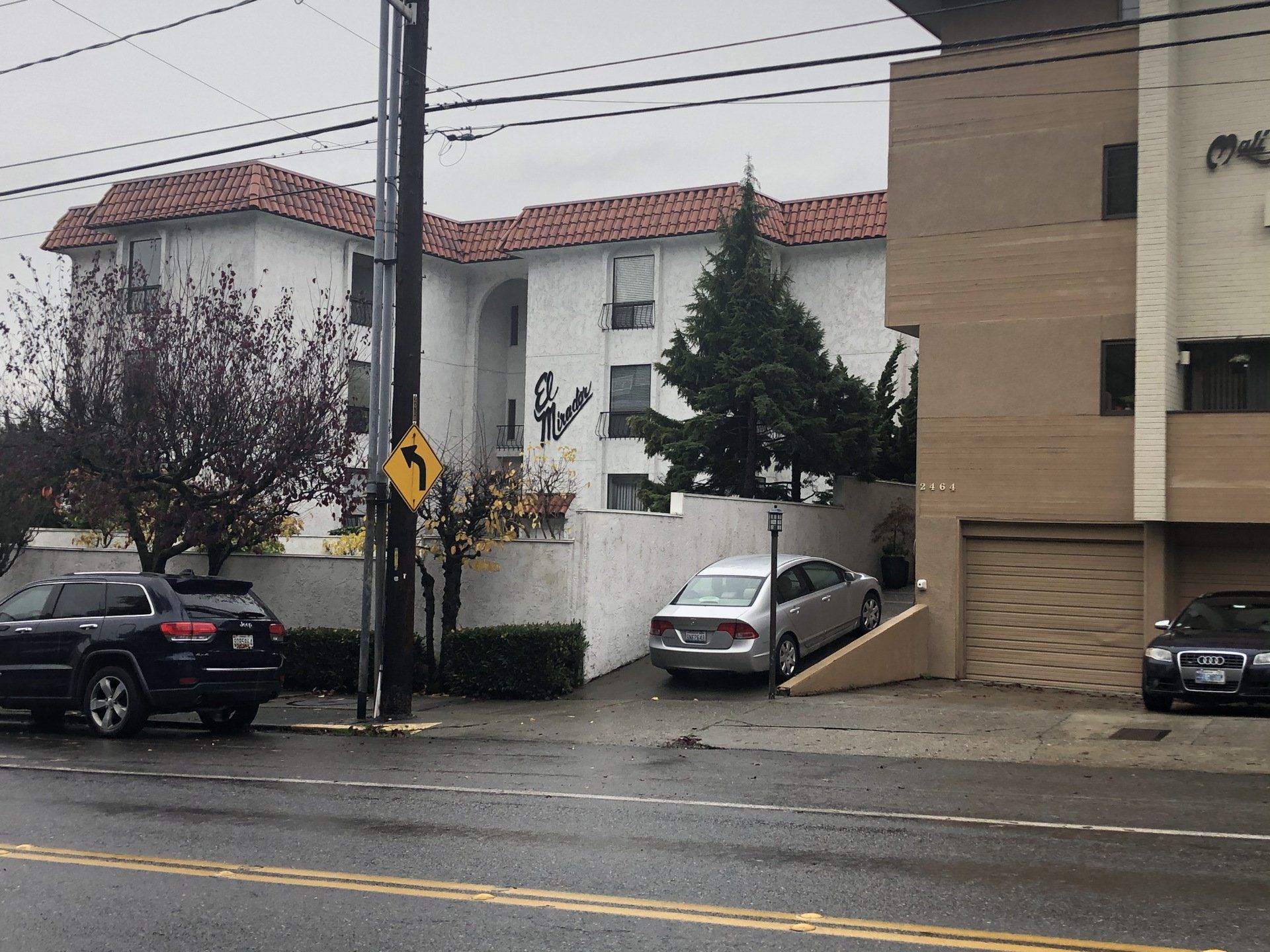 Cars are parked on the side of the road in front of a building