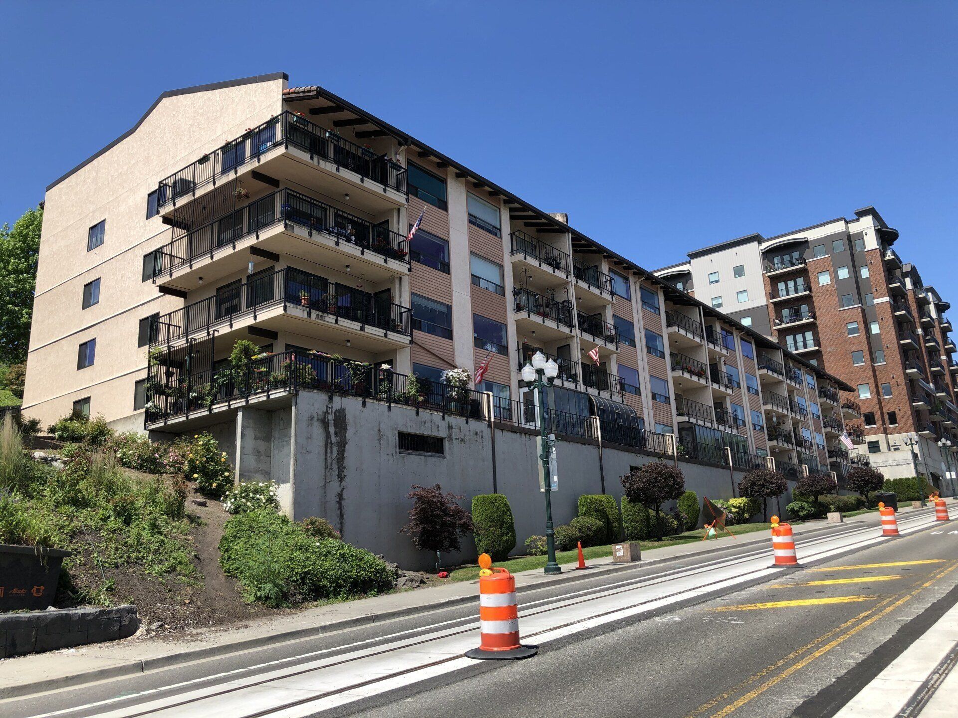 A large apartment building is sitting on a hill next to a road.