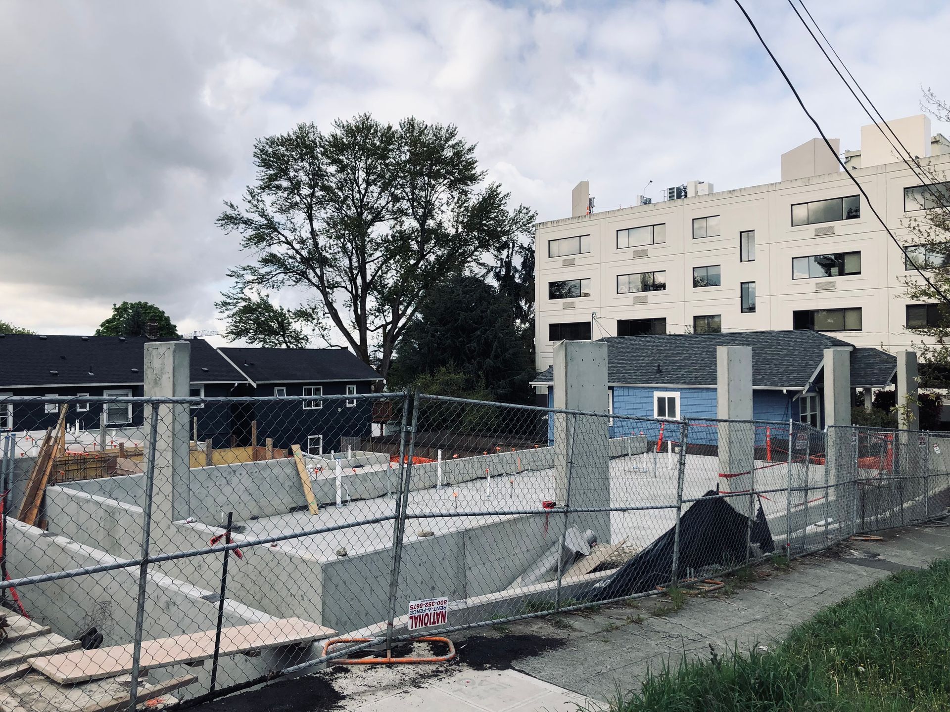 A construction site with a chain link fence and a building in the background.