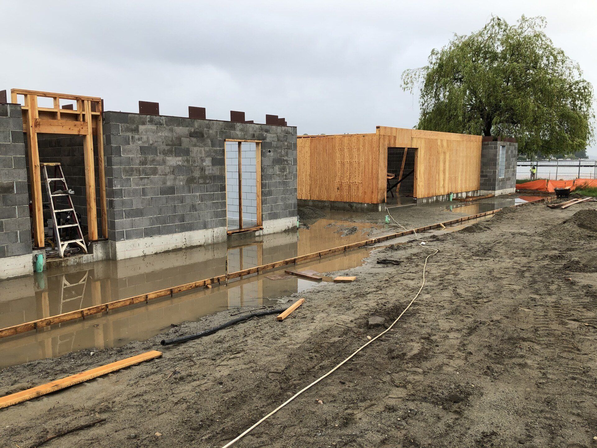 A construction site with a lot of water and a tree in the background.