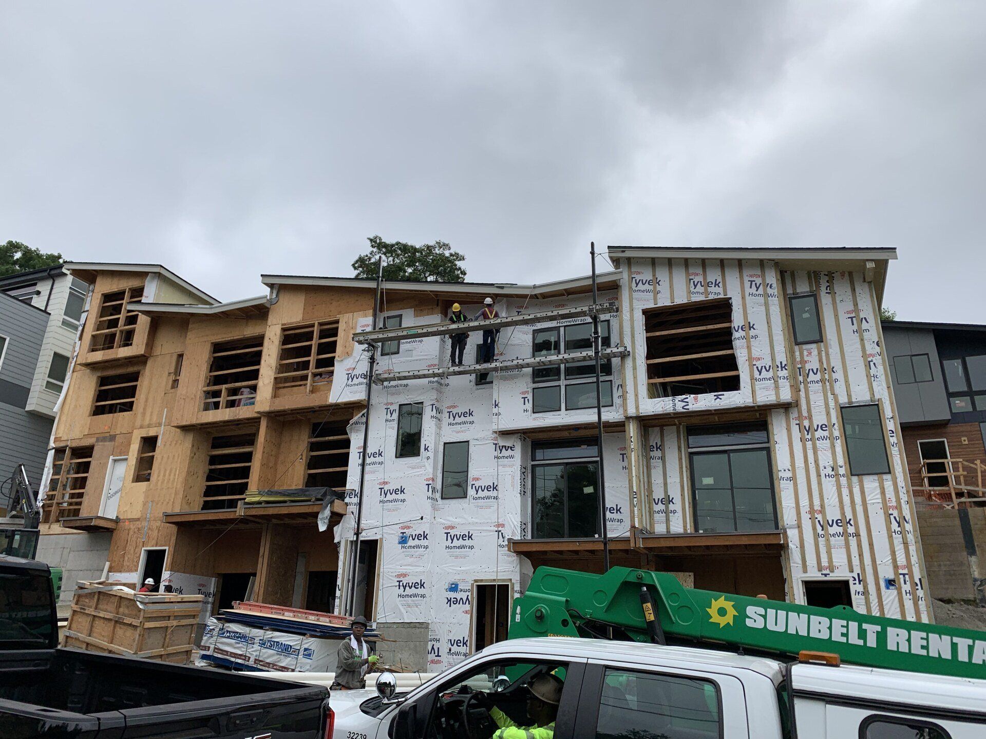 A white truck is parked in front of a building under construction.