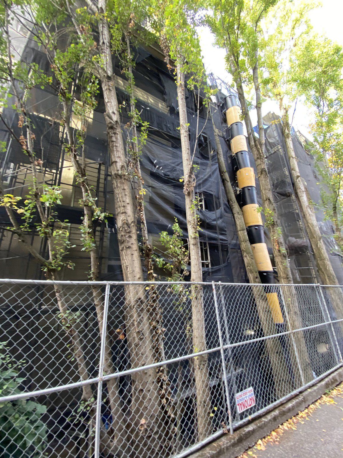A chain link fence is surrounded by trees and a building.