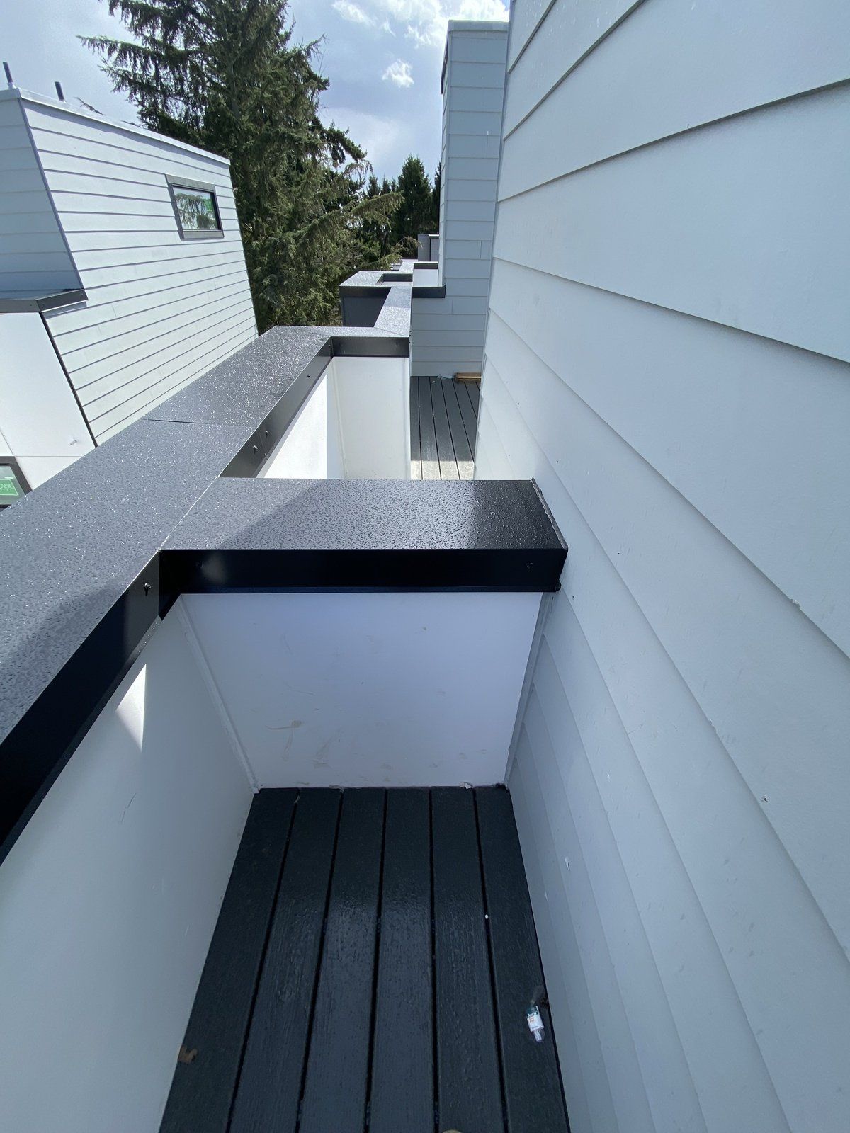 A balcony with a wooden floor and a white building in the background