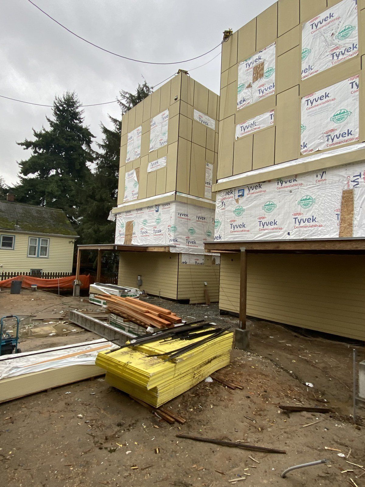 A building under construction with a lot of wood in front of it.