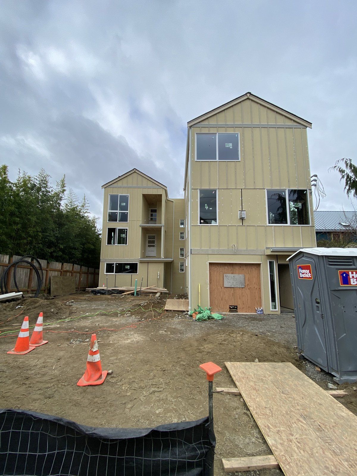 A large house is being built in the middle of a dirt field.