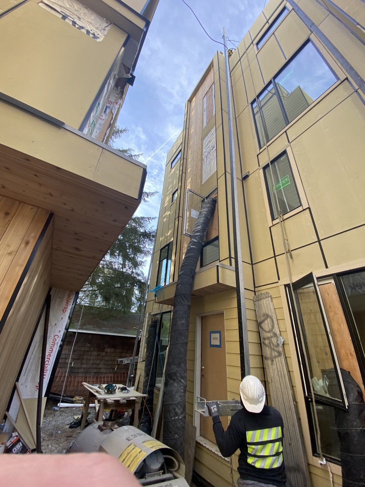 A man is standing in front of a building with a hose attached to it.