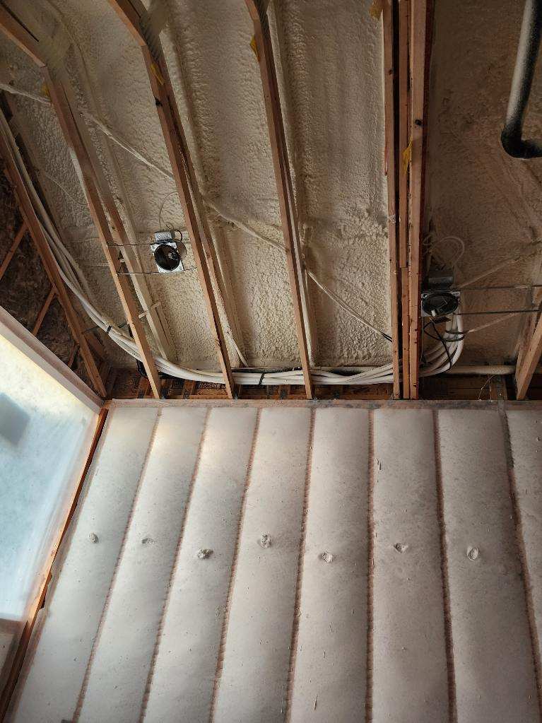 The ceiling of a house is being insulated with foam.