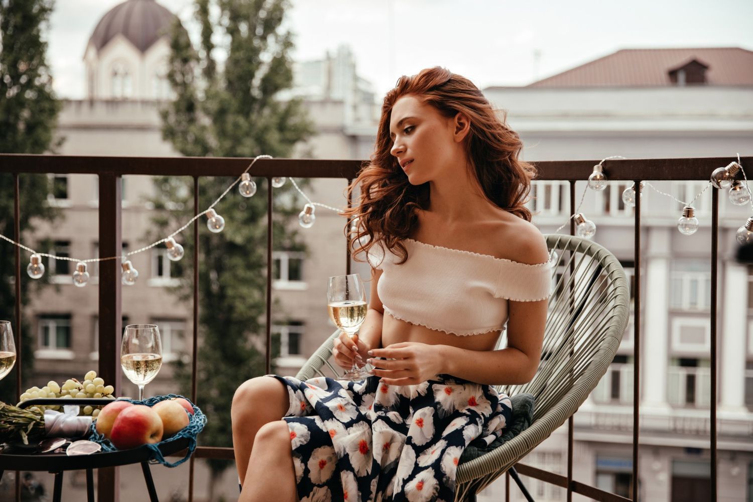 A woman is sitting on a balcony holding a glass of wine.