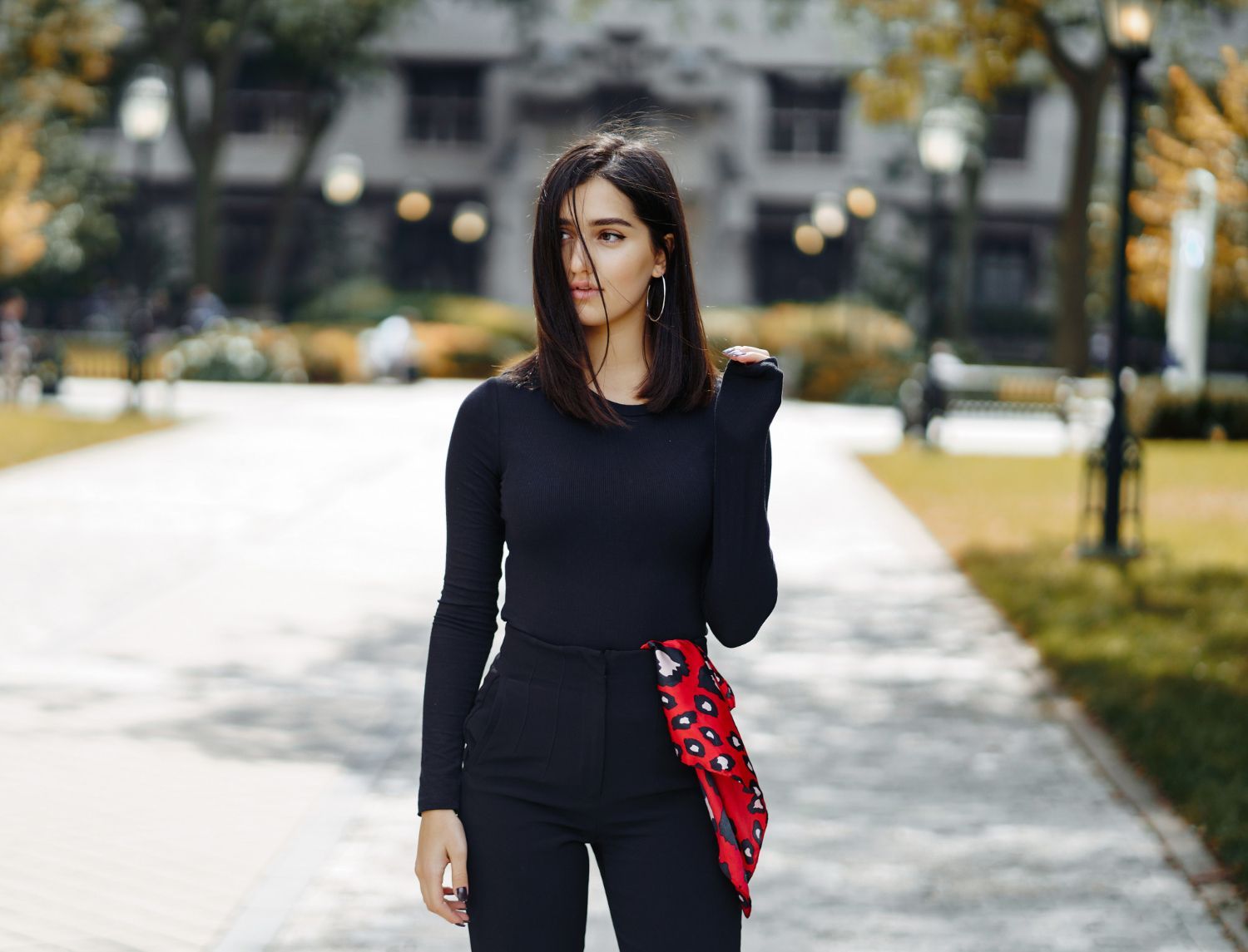 A woman in a black top and black pants is walking down a sidewalk.