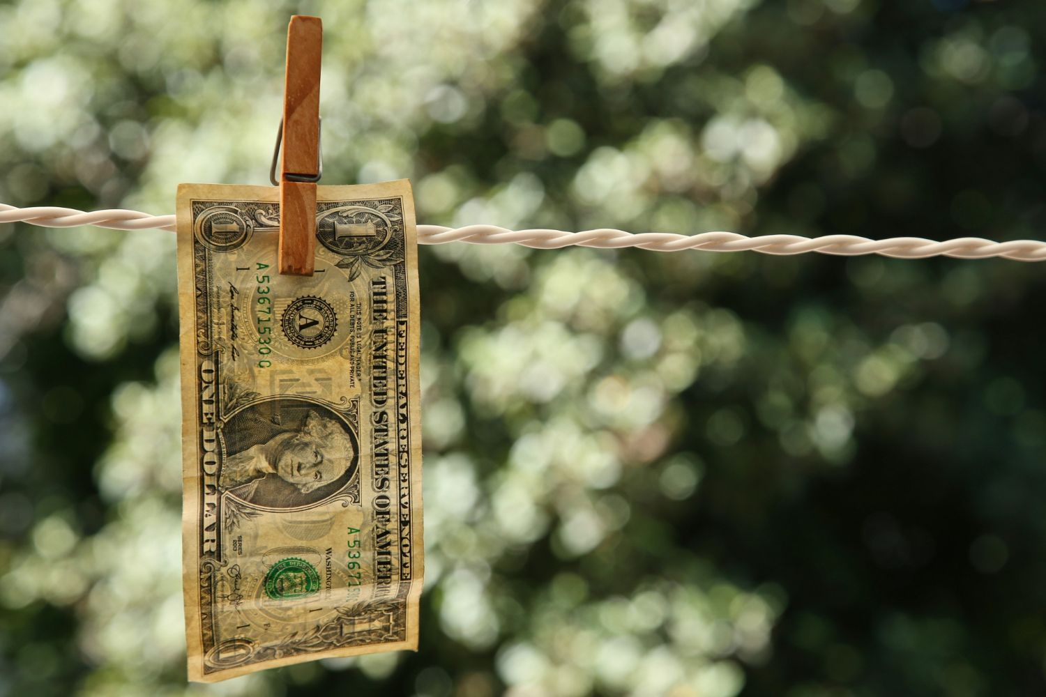 A dollar bill is hanging on a clothes line.
