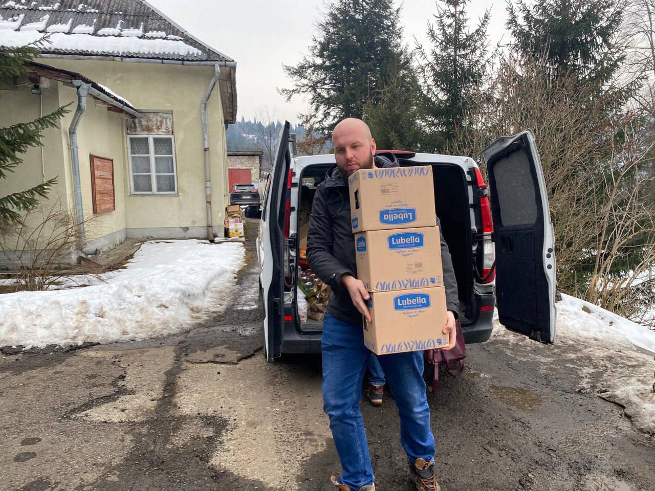 A man is carrying boxes out of the back of a van.