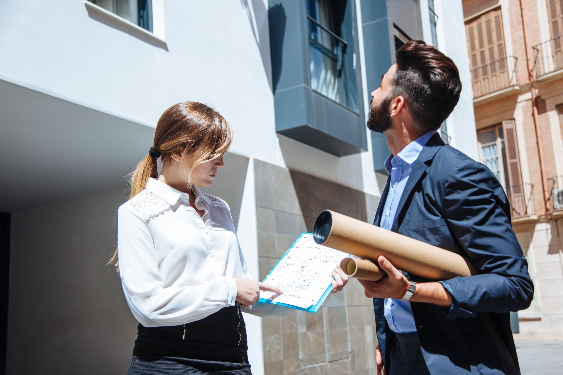 A man and a woman are standing next to each other in front of a building.
