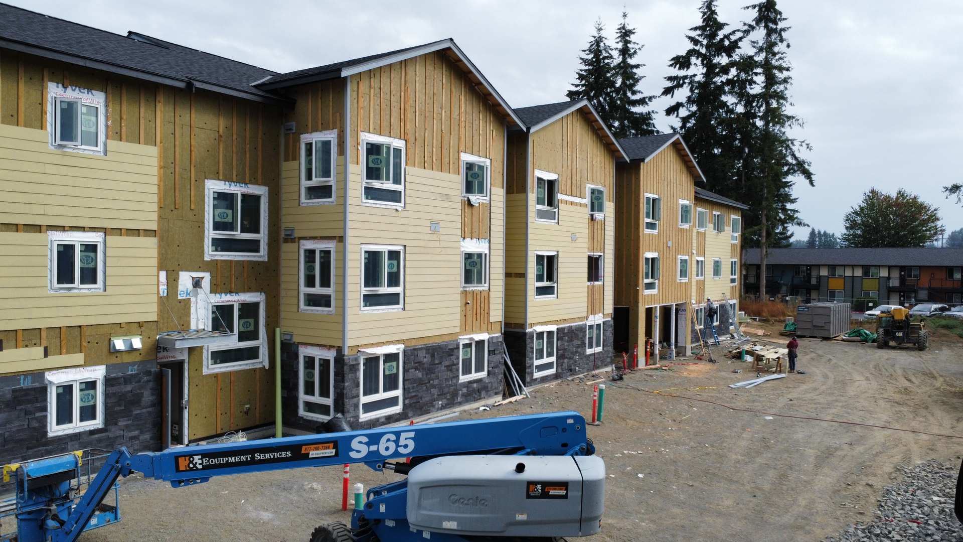 A large building under construction with a blue crane in front of it.