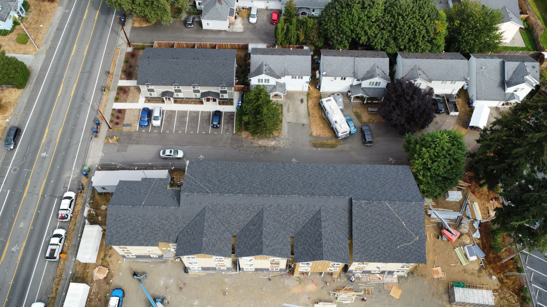 An aerial view of a building under construction with a lot of cars parked in front of it.