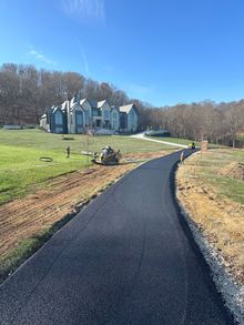 A large house is sitting on top of a hill next to a road.