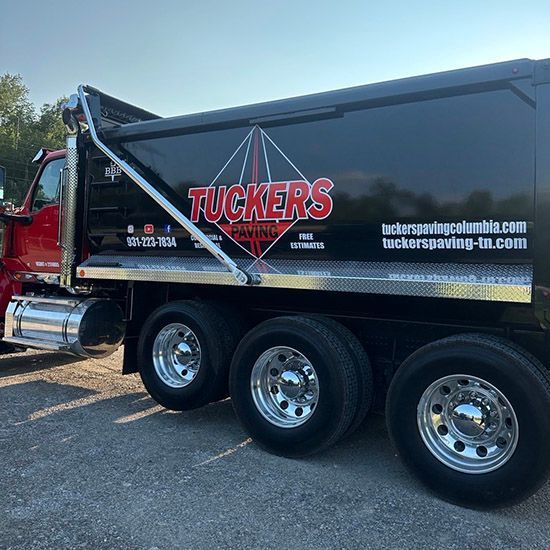 A tucker 's dump truck is parked in a parking lot.