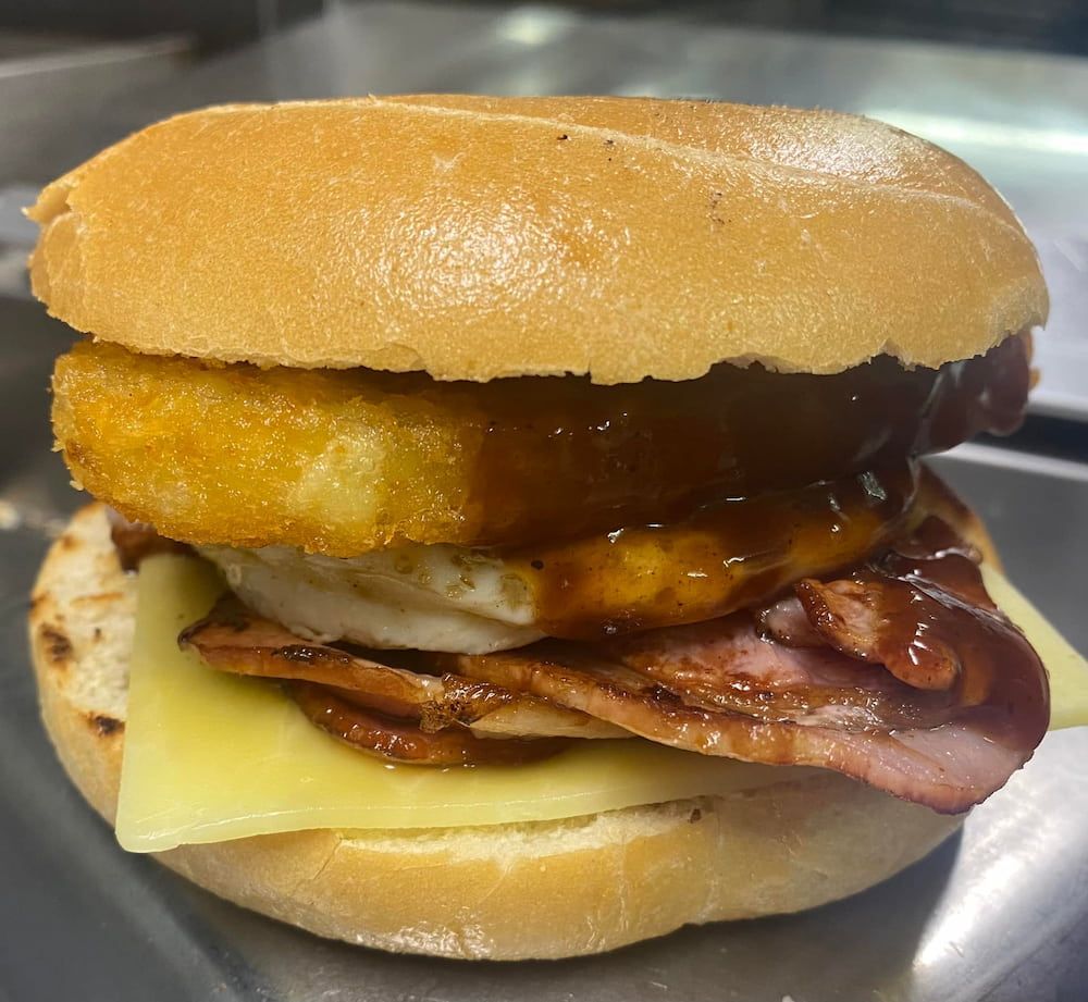 A Sandwich With Bacon, Egg, Cheese And Onion Rings On A Bun — Cedar Park Bakehouse in Taranganba, QLD