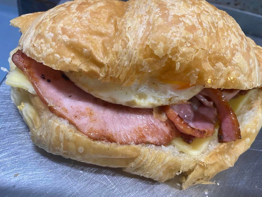 A Ham And Egg Sandwich On A Croissant On A Table — Cedar Park Bakehouse in Taranganba, QLD