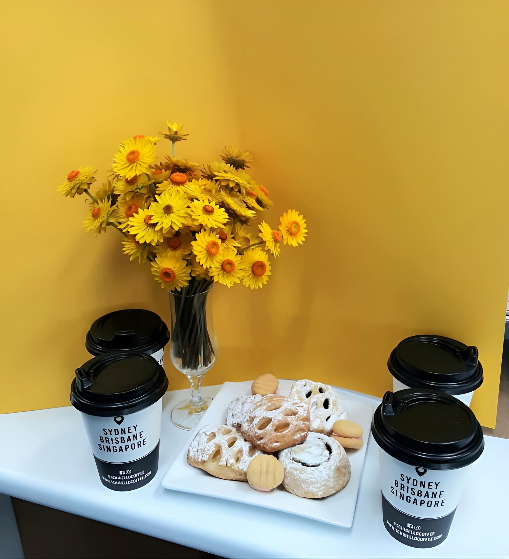 A Table With Three Cups Of Coffee And A Vase Of Flowers — Cedar Park Bakehouse in Taranganba, QLD