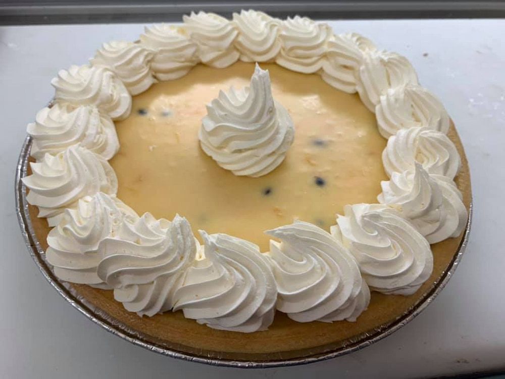 A Cheesecake With Whipped Cream On Top Is Sitting On A Table — Cedar Park Bakehouse in Taranganba, QLD