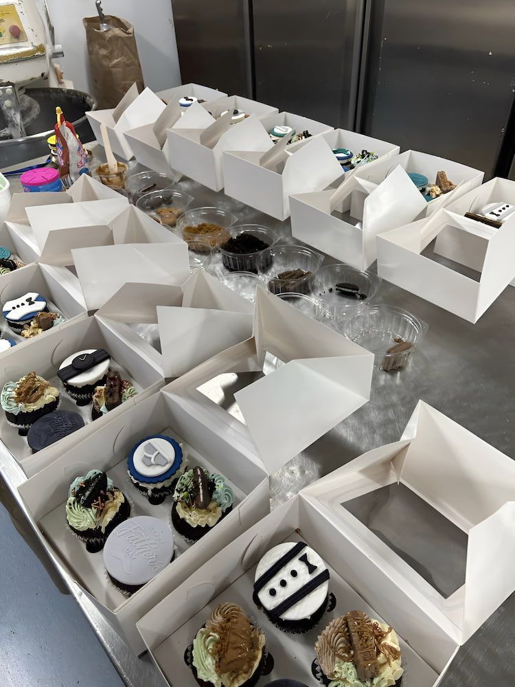 A Bunch Of Cupcakes In Boxes On A Table — Cedar Park Bakehouse in Taranganba, QLD