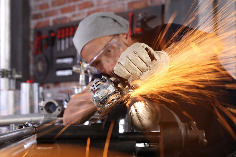 a man is using a grinder to cut a piece of metal .