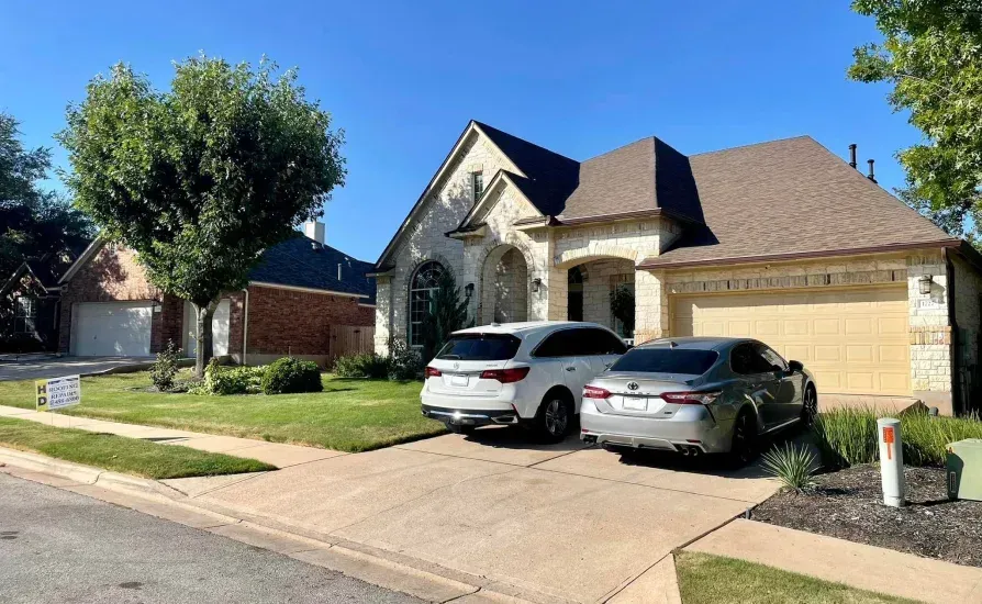 Suburban home with two cars parked in driveway on a sunny day.
