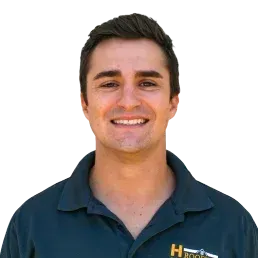 Smiling man in a dark blue polo shirt, against a yellow background.