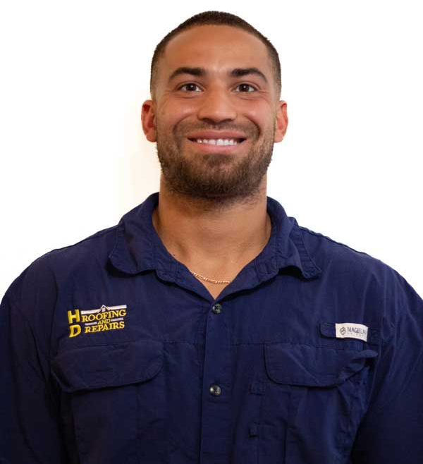 Man smiling, wearing a blue work shirt with logos.