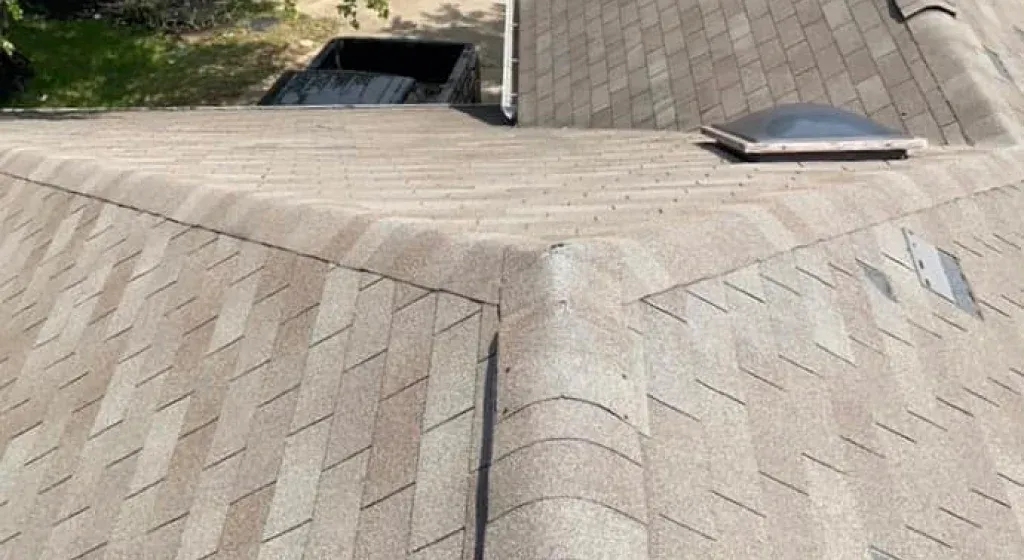 Overhead view of a shingled roof with a skylight and vent, showing a brown and tan color scheme.