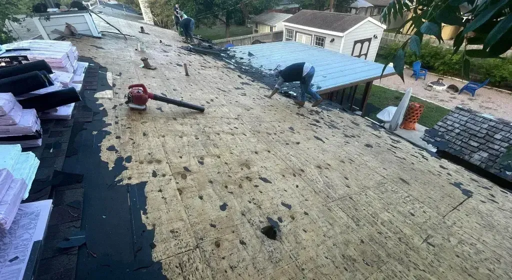 Roof being prepared for new shingles; person using a blower; materials and tools visible.