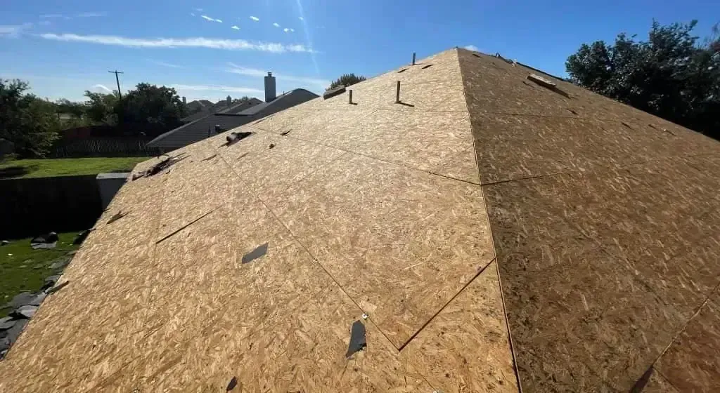 Roof partially covered with new plywood on a sunny day.