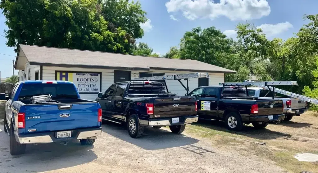 Blue and black pickup trucks parked outside a one-story building on a sunny day.