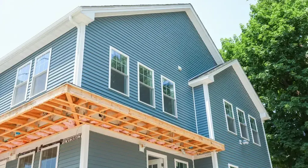Blue house under construction with exposed wooden frame.