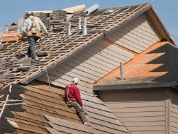 Home with blue corrugated metal roof replacement in progress; materials on the lawn.